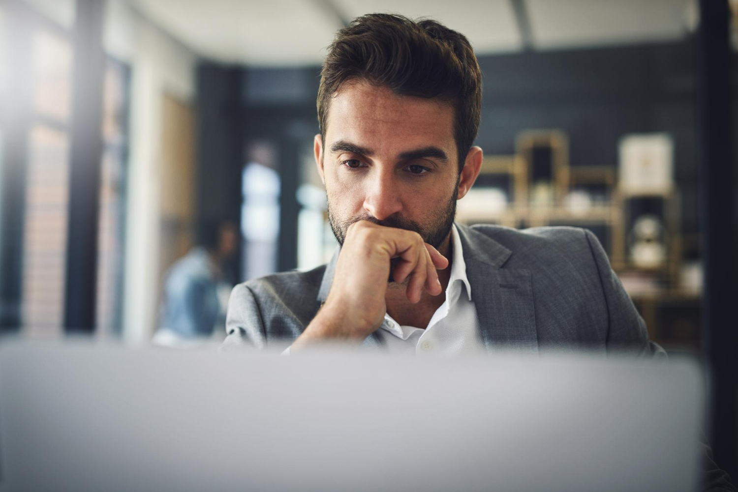 Homem pensativo em frente ao computador, refletindo sobre executive search para posições de diretoria no mercado brasileiro.